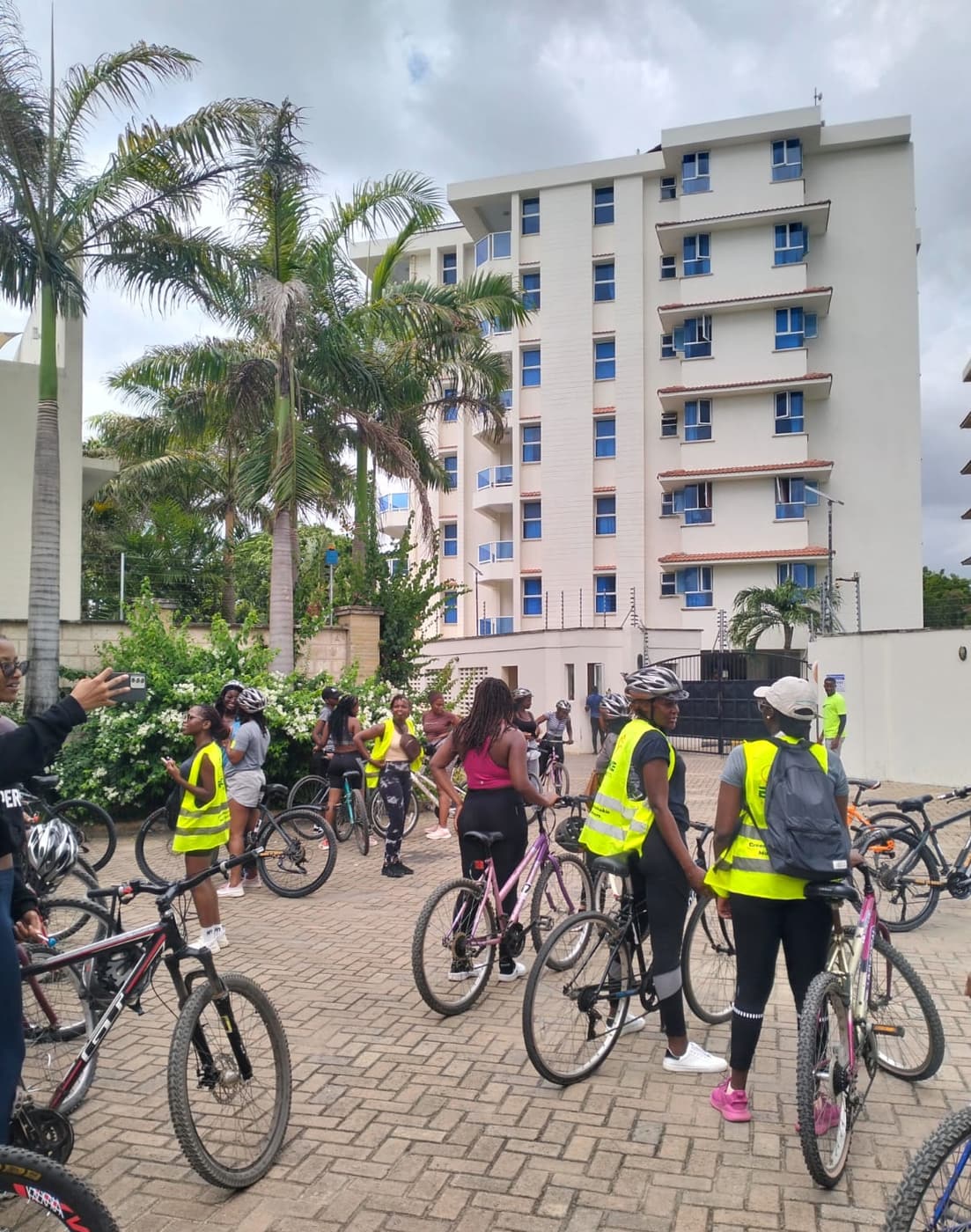 Girls with their bikes gathering under the palms before the girls' ride sets off