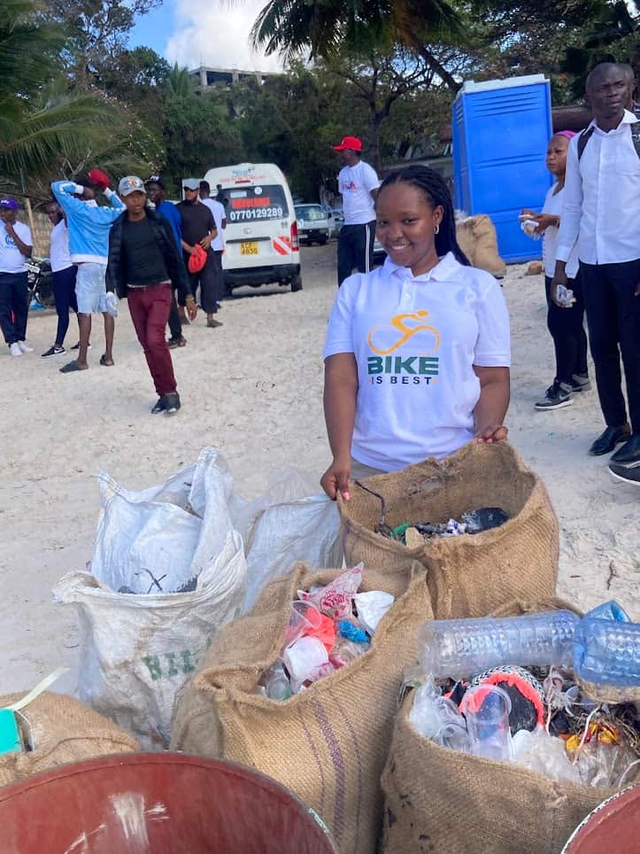 A volunteer in a Bike is Best t-shirt sorting collected rubbish into sacks on the beach