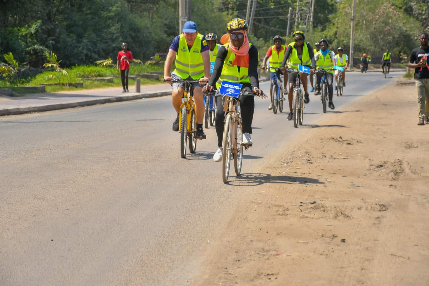 Riders on a sandy road between palms